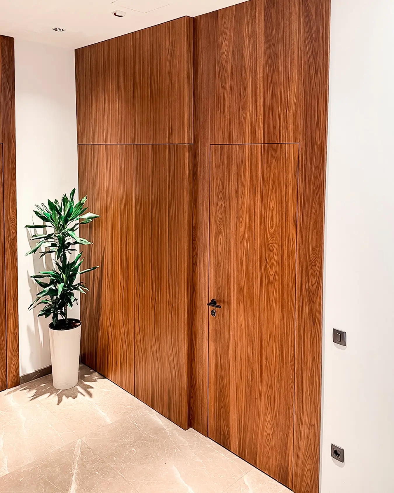 Verdeckte Türen in einer durchgehenden Holzwandverkleidung
